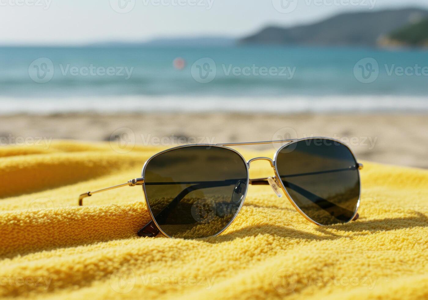 Aviator sunglasses rest on a yellow towel, offering a stylish shield against the sun on the beach. photo