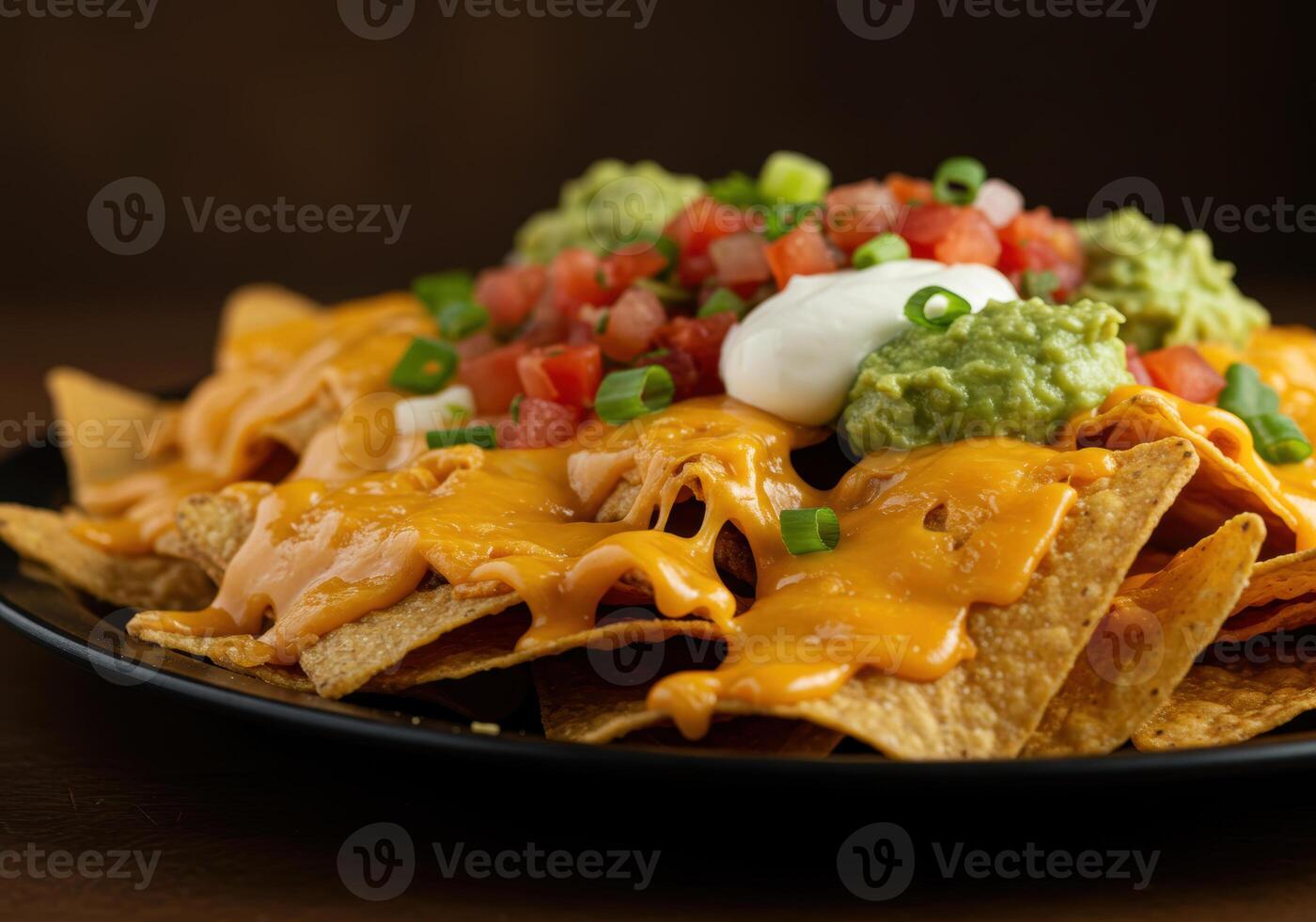 A delicious plate of loaded nachos generously topped with cheese, guacamole, and pico de gallo. photo