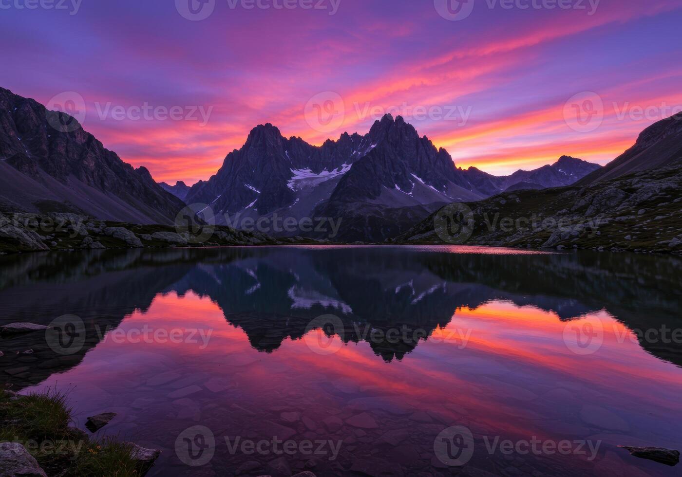 Majestic mountain peaks are perfectly reflected in a calm alpine lake at dusk during a colorful sunset. photo
