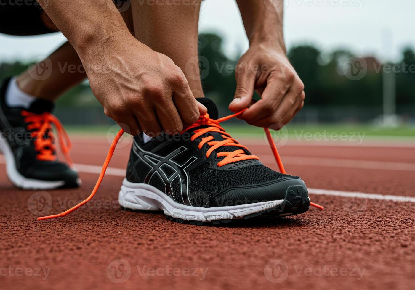 A runner carefully ties the orange laces of their running shoes photo