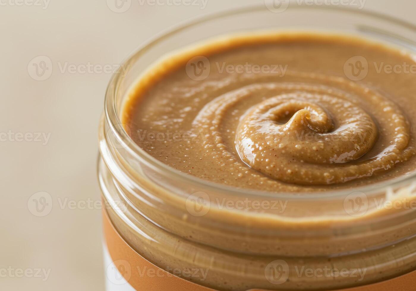 A jar of freshly made almond butter shows its creamy texture with a delectable swirl on top photo