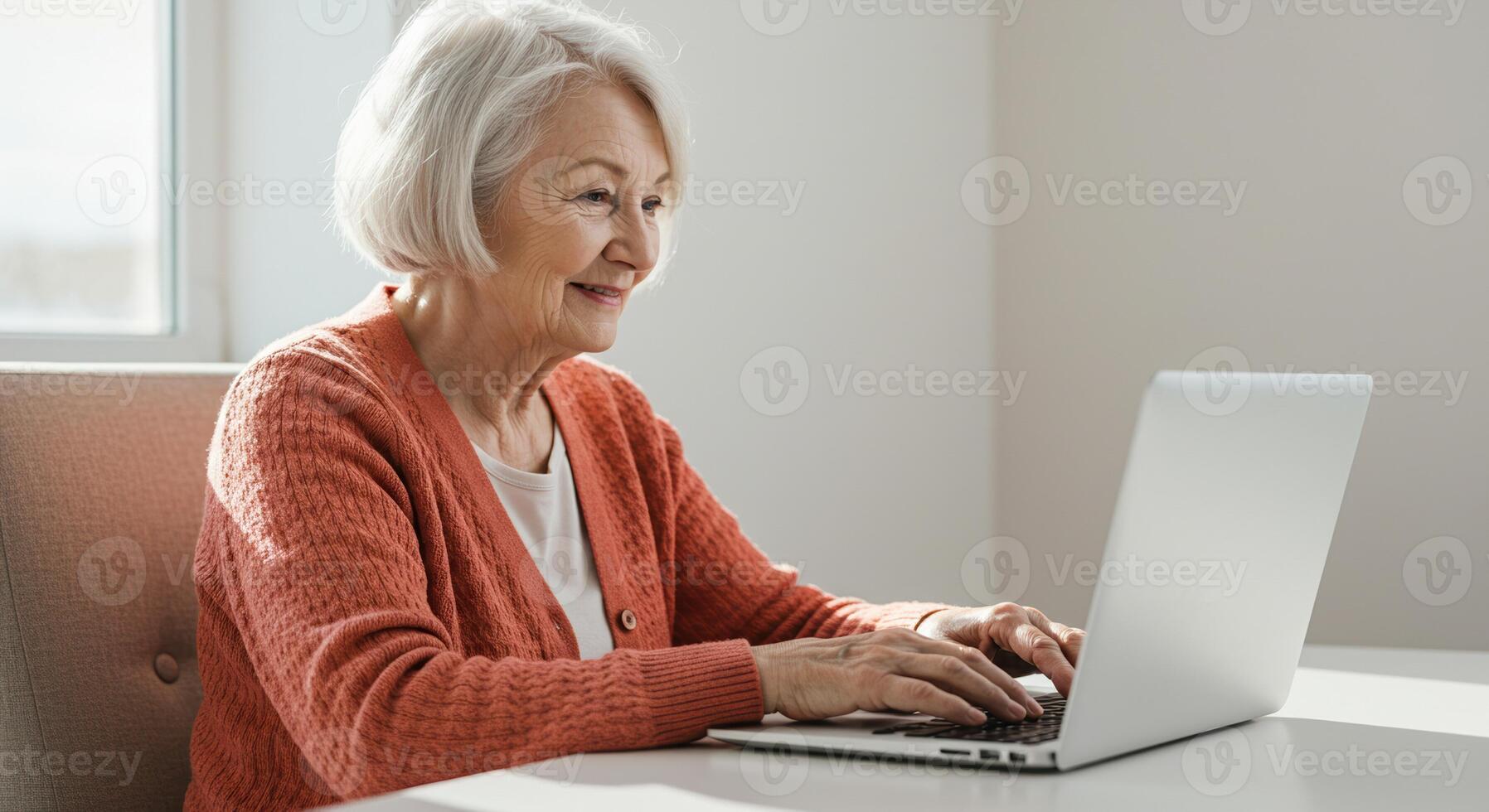 An attractive older woman is happily using her laptop, likely working or connecting with loved ones. photo