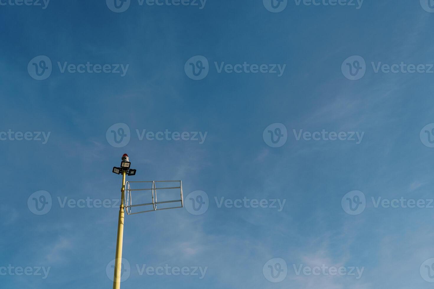 Antenna on a pole with searchlights and a signal lantern on the top against the sky photo