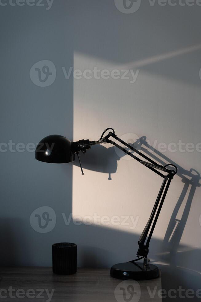 Stylish black lamp from Ikea on the wooden table with sun reflect on the background photo
