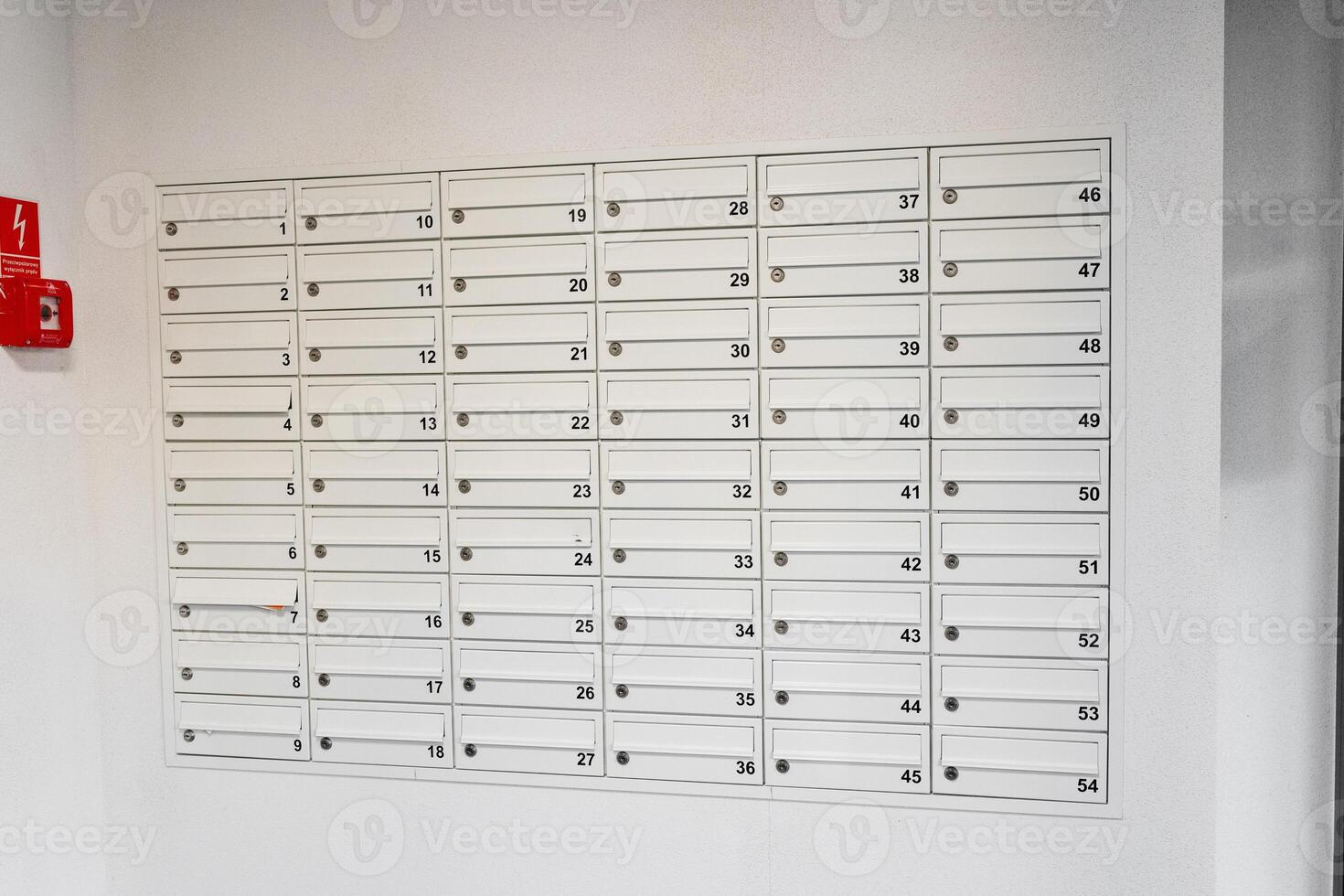 Row of white mailboxes with letters sticking out from one slot. Indoor hallway mailbox system in a residential building. Mail delivery and correspondence concept. photo