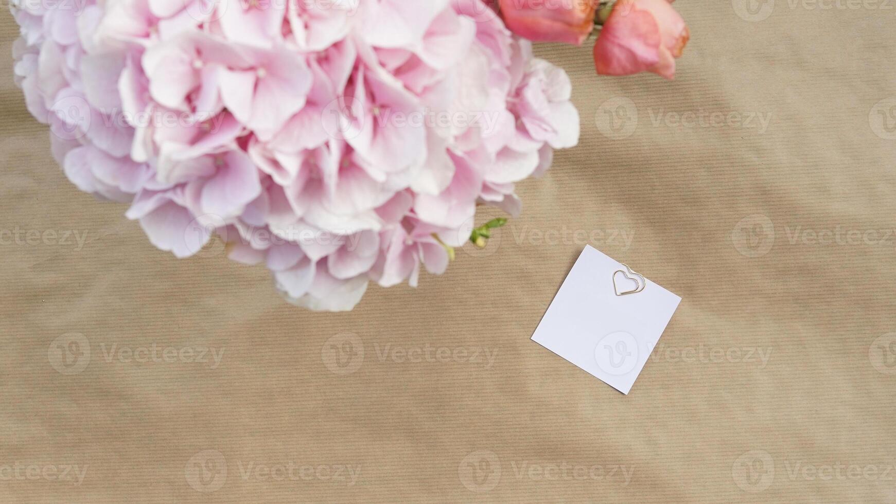 Blank white card mockup template with pink flowers with beige paper background. Top view. Modern trend template for advertising. photo