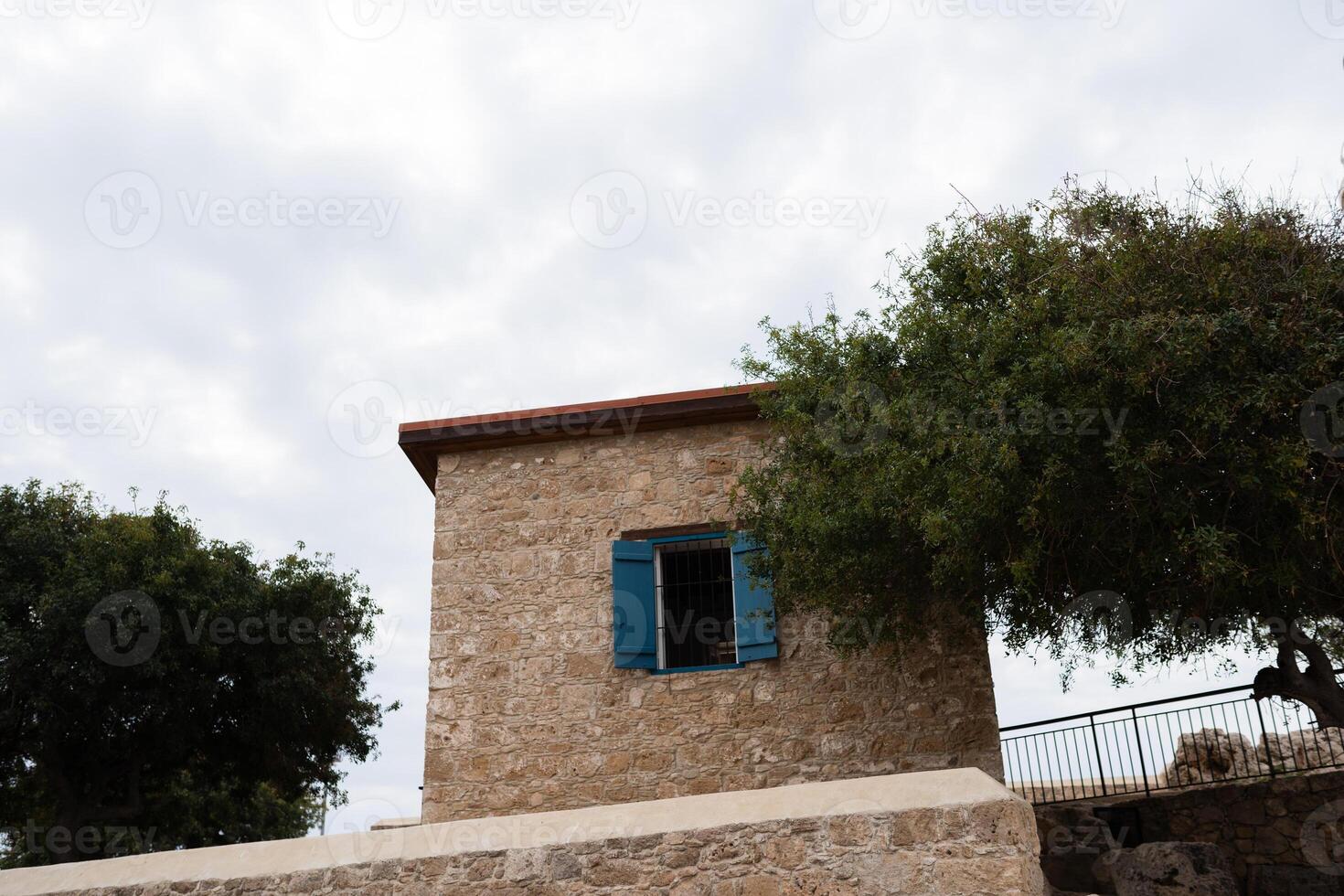 View of house with orange tile roofs,blue exterior window shutter surrounded by olive trees in Cyprus photo