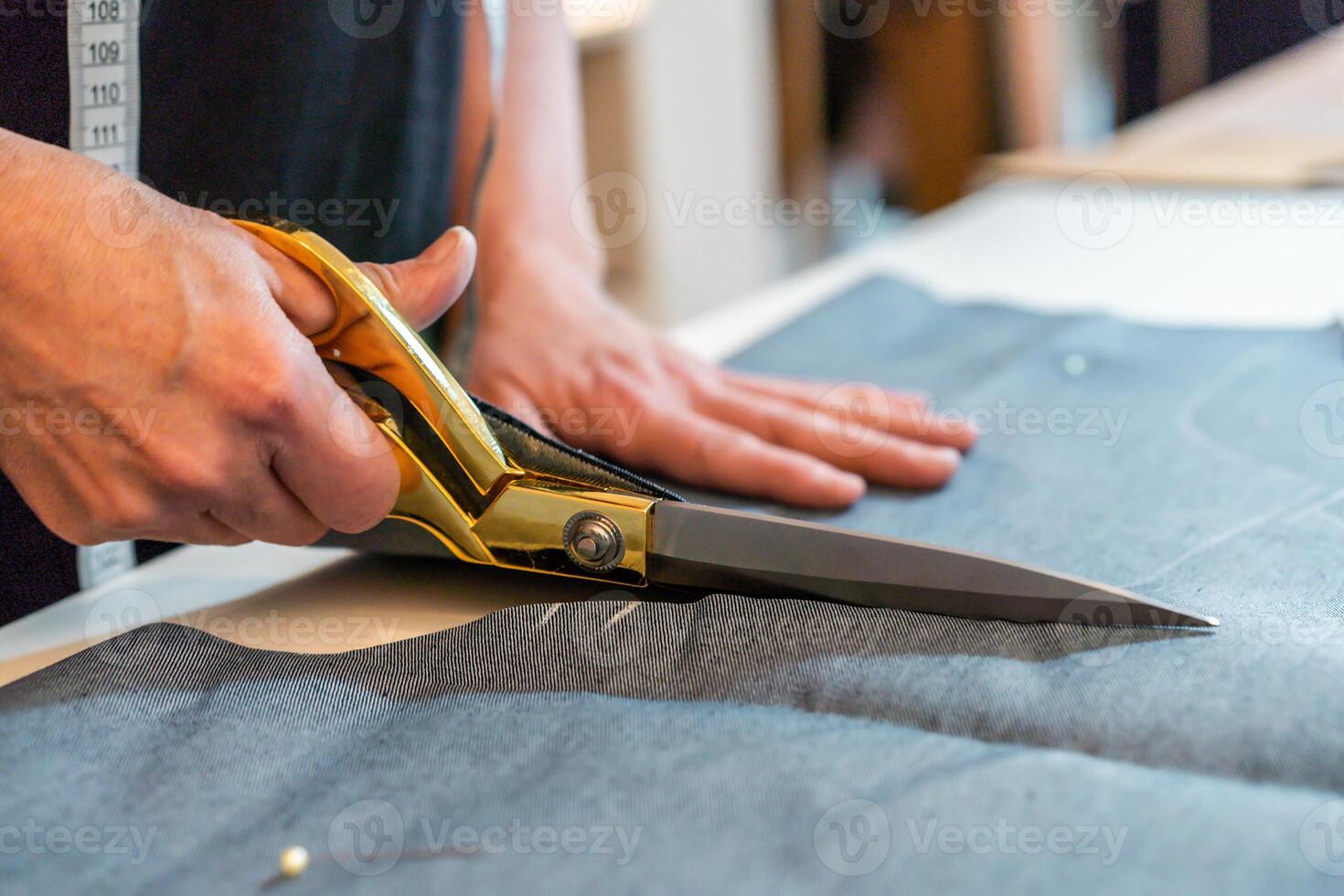 A person cutting fabric with a pair of scissors photo