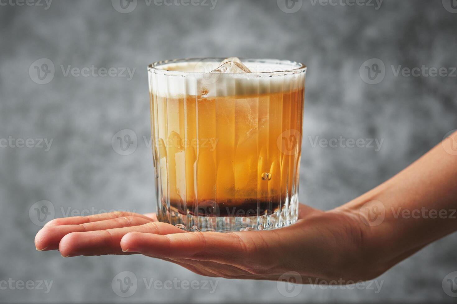 A person holding a glass of orange drink photo