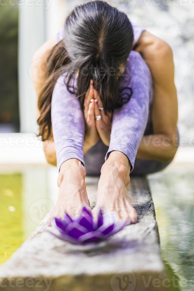 A woman in purple yoga pants sitting on a wooden ledge photo