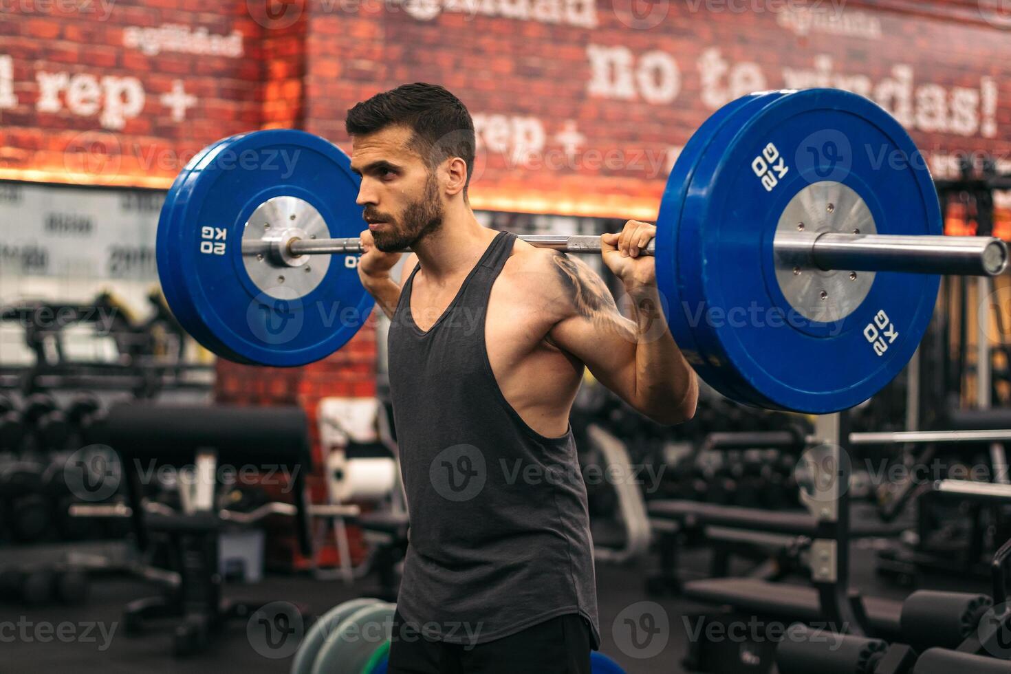 concentrated man athlete doing squats in a gym. front view photo
