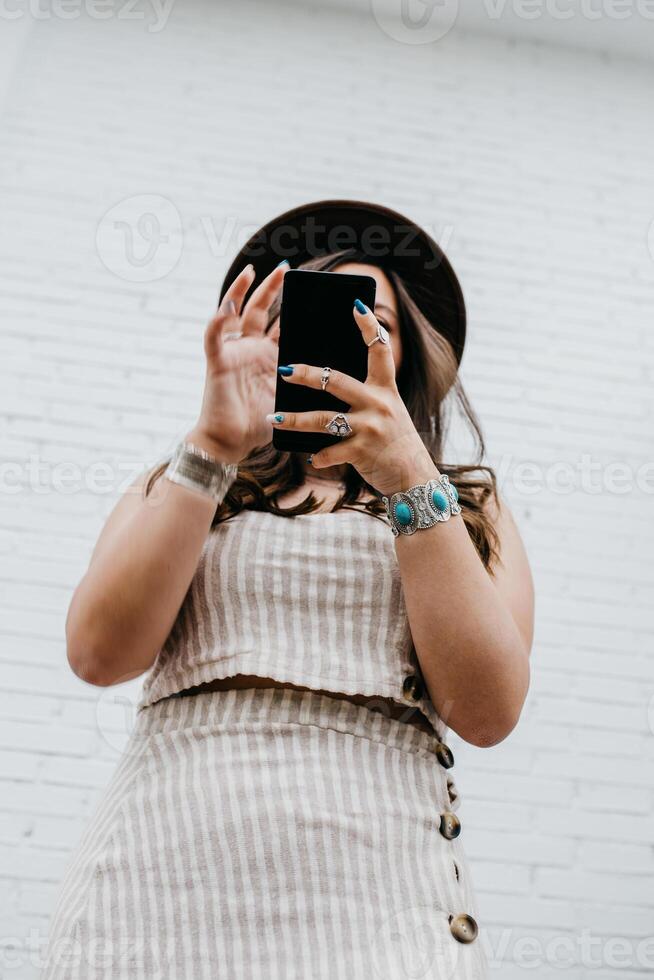 Woman in hat smiling browsing smartphone photo