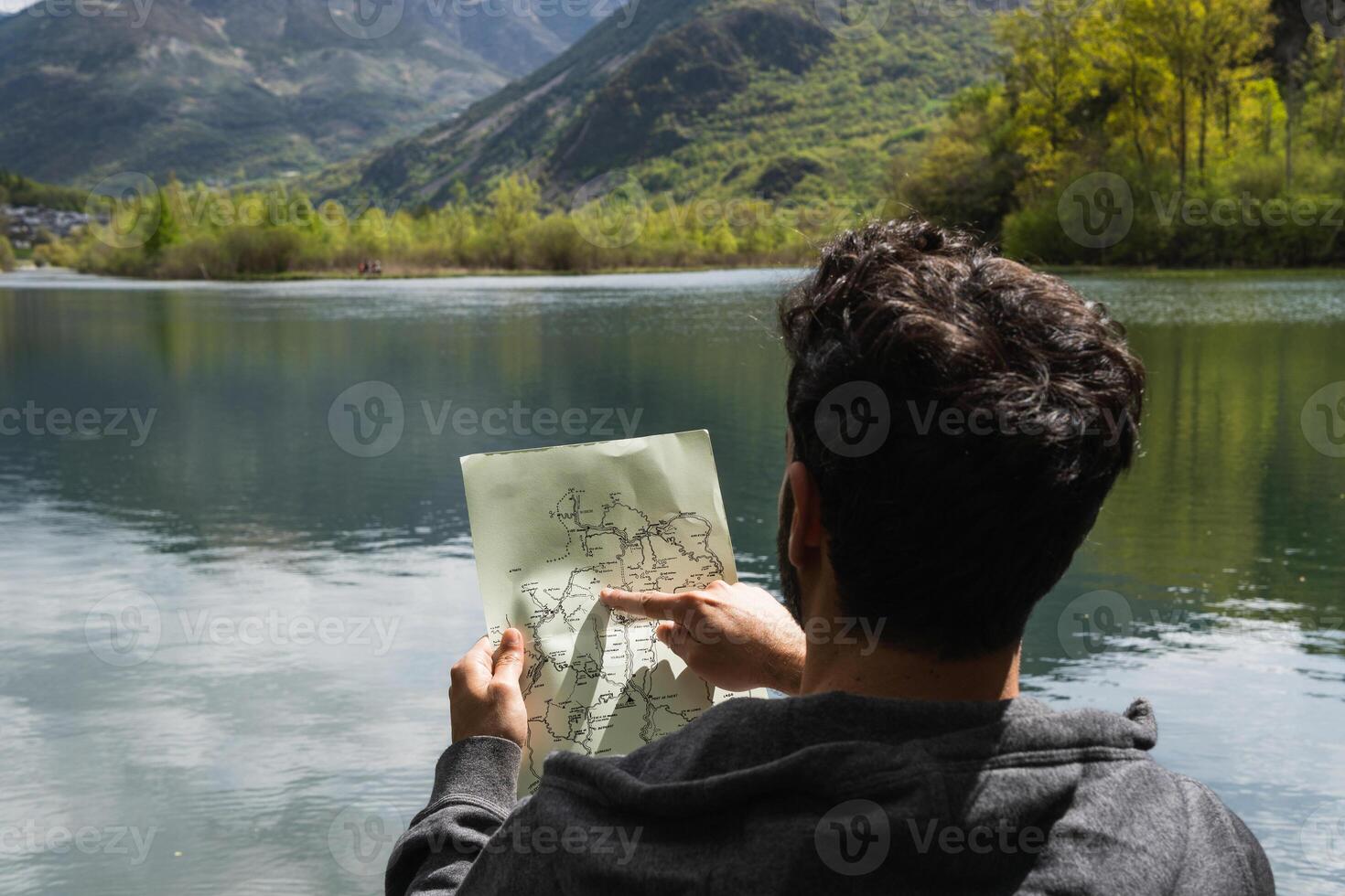 Traveling man reading map near lake in highlands photo
