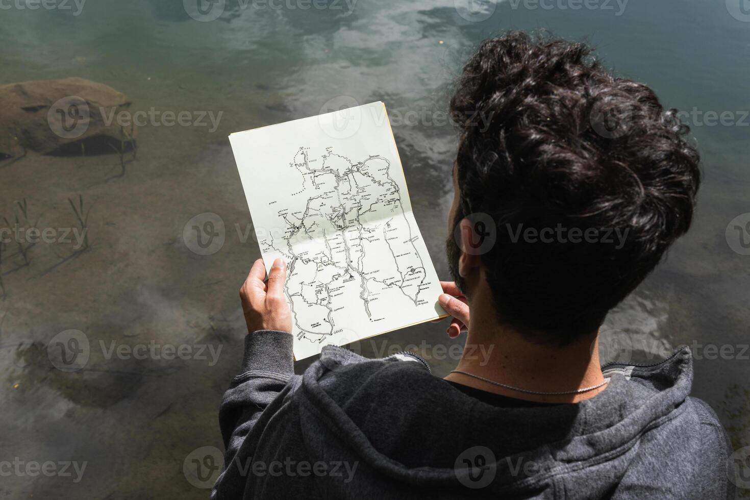 Traveling man reading map near lake in highlands photo