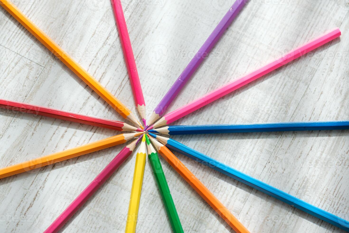 Coloured pencils arranged in a circle on a wooden background photo