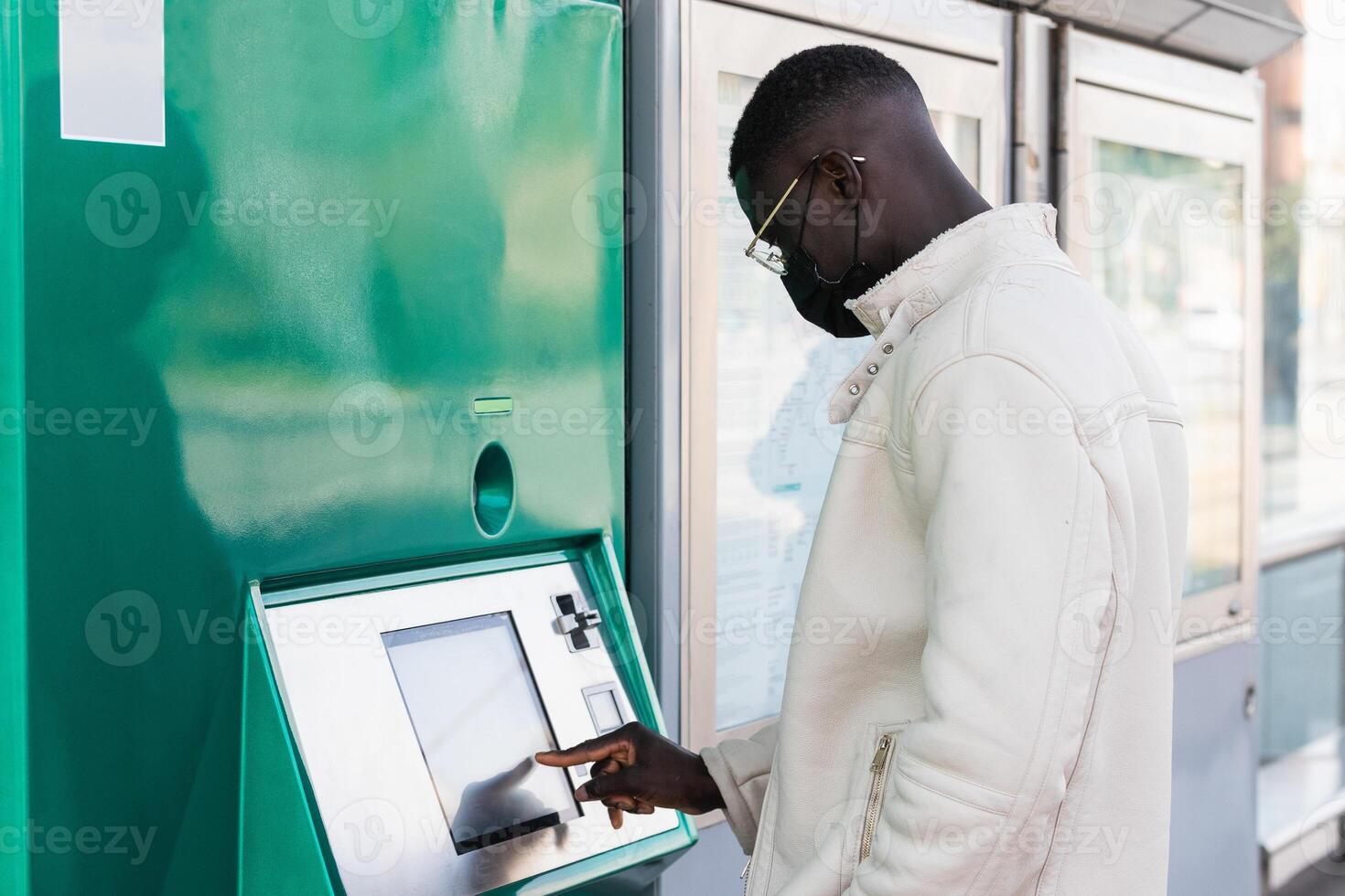 Black businessman touching screen of ATM in town photo