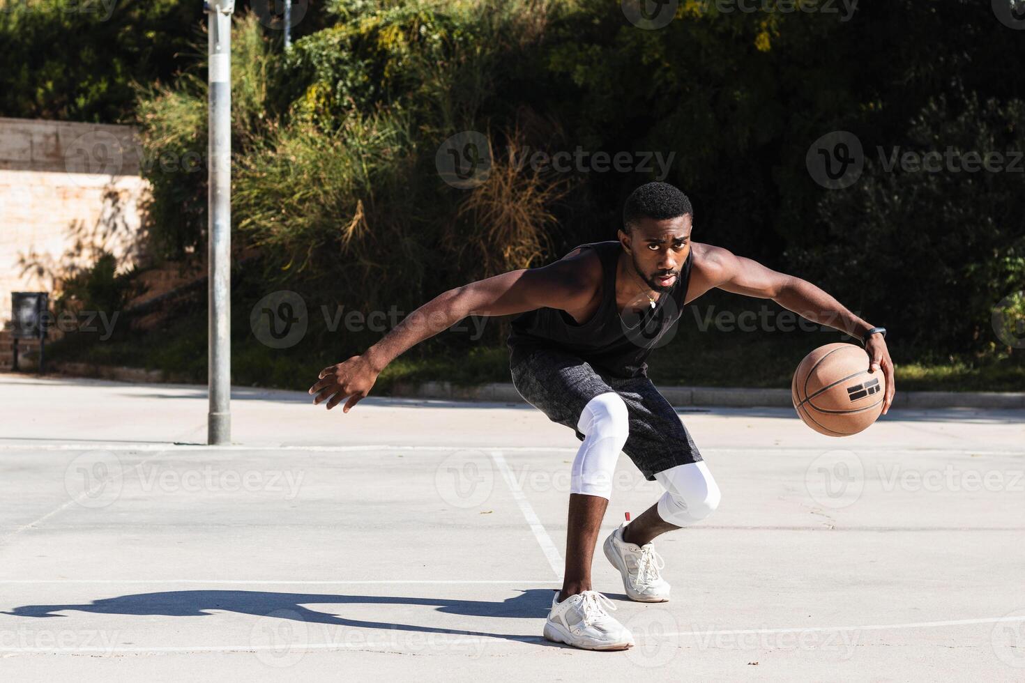 Black man playing basketball on sports ground photo