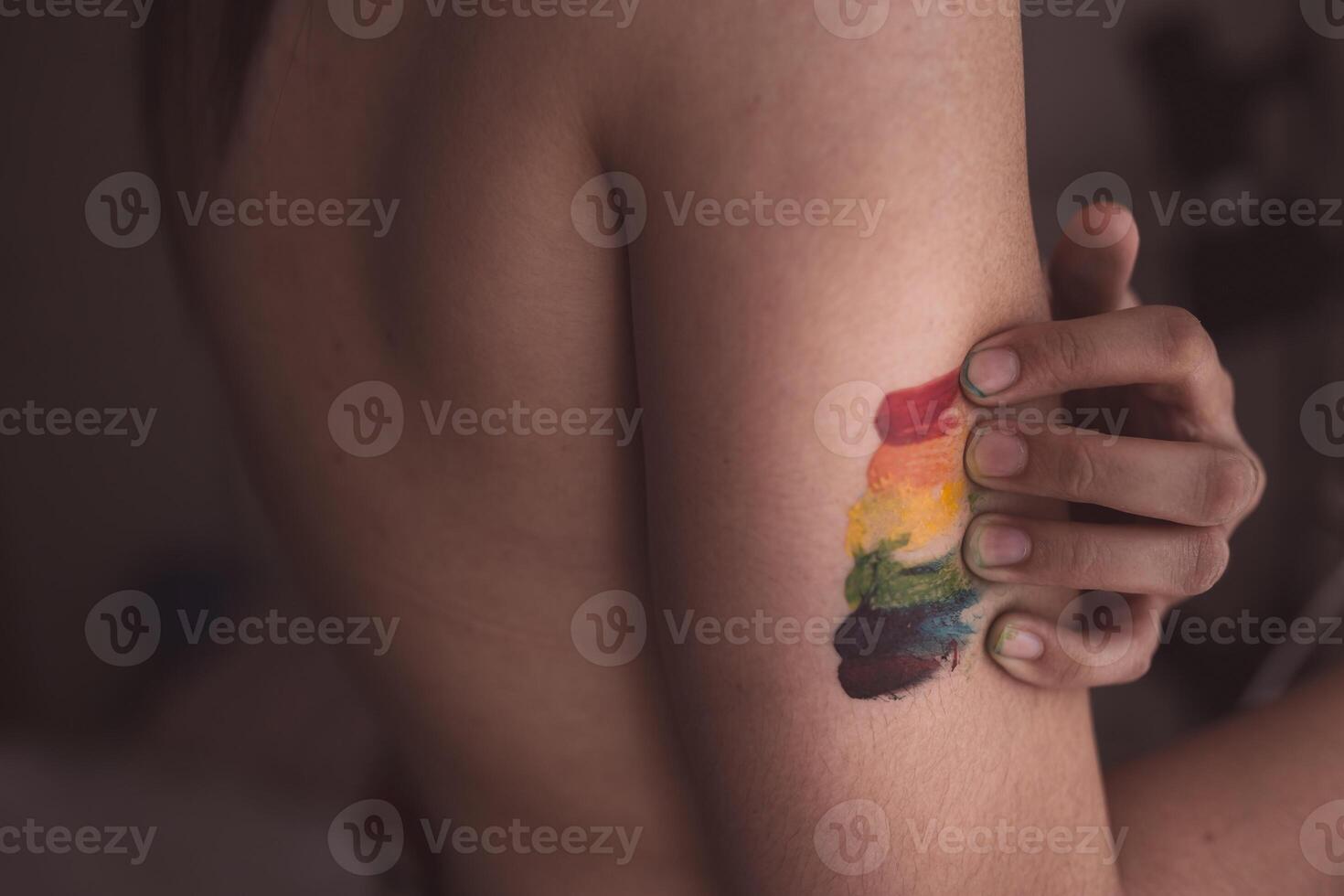 Attractive naked woman covering breast and drawing LGBT symbol photo