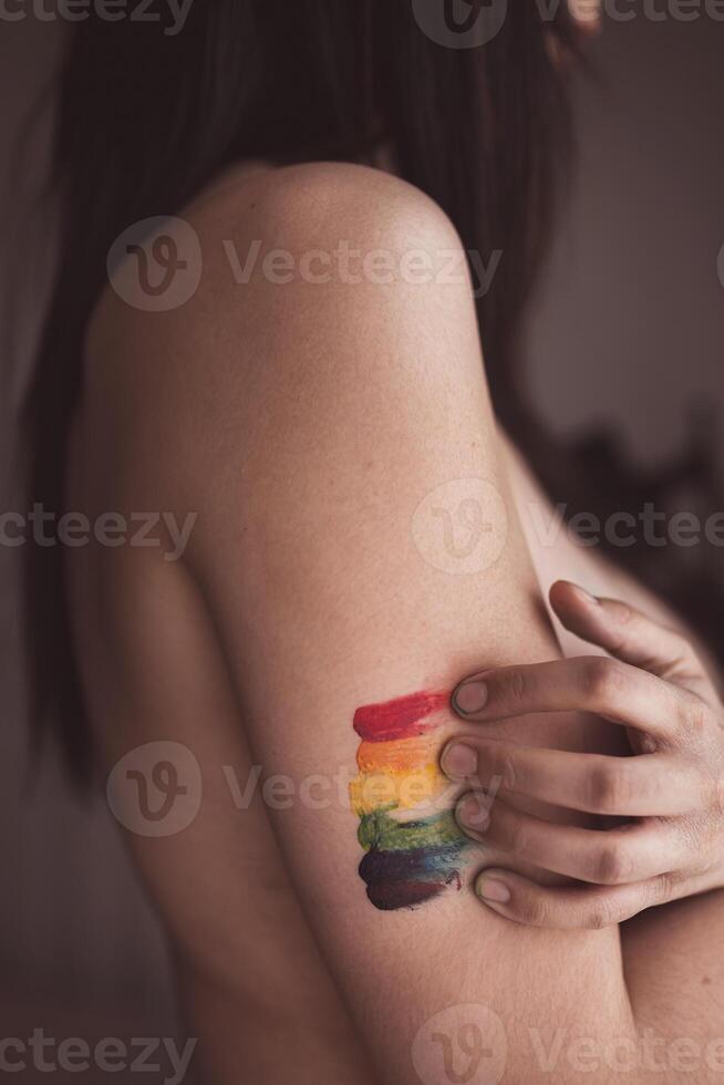 Attractive naked woman covering breast and drawing LGBT symbol photo