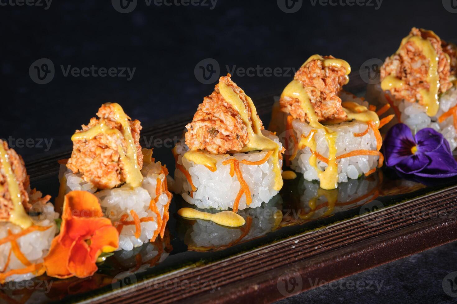 Appetizing sushi topped with salmon and fresh sauce served on wooden tray photo