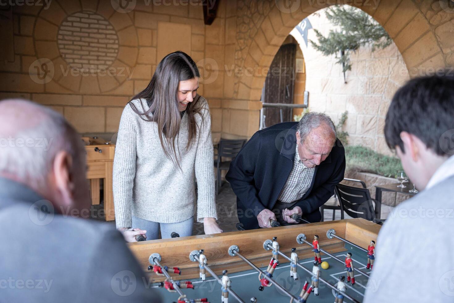 A granddaugther and his grandfather are playing table football game photo
