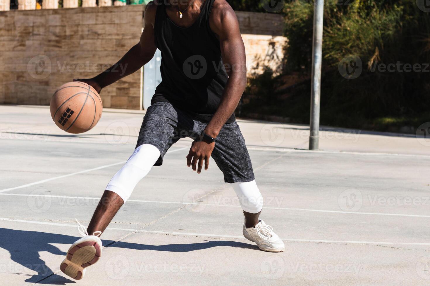 Anonymous black man playing basketball on sports ground photo