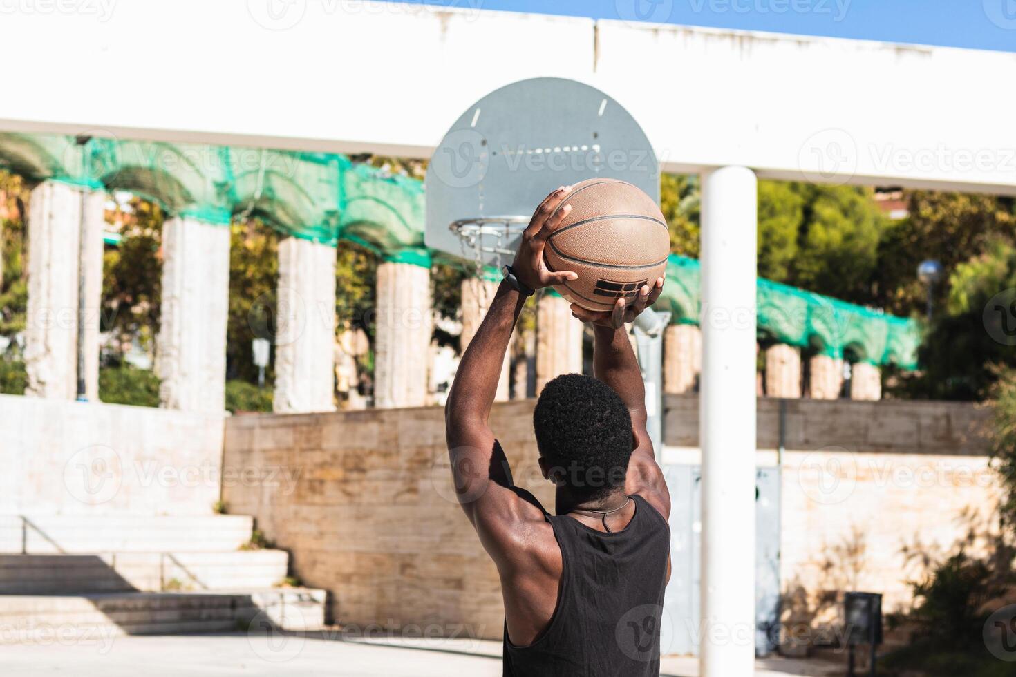 Anonymous black man playing basketball on sports ground photo