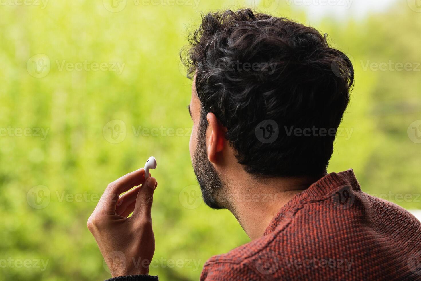 Anonymous man with earbuds against green background photo
