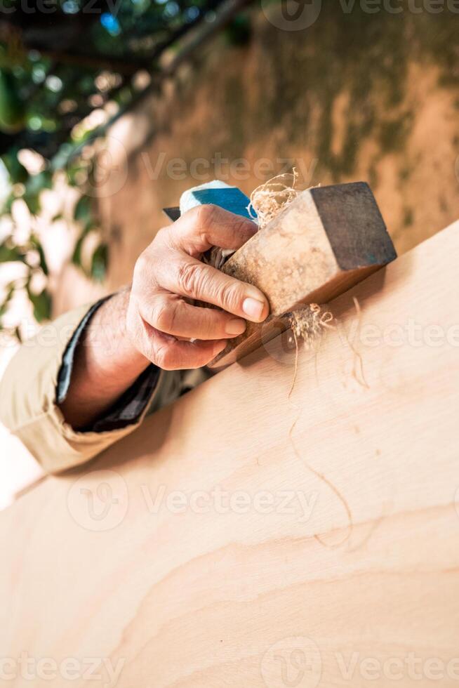 Anonymous senior man shaping wood with plane tool photo