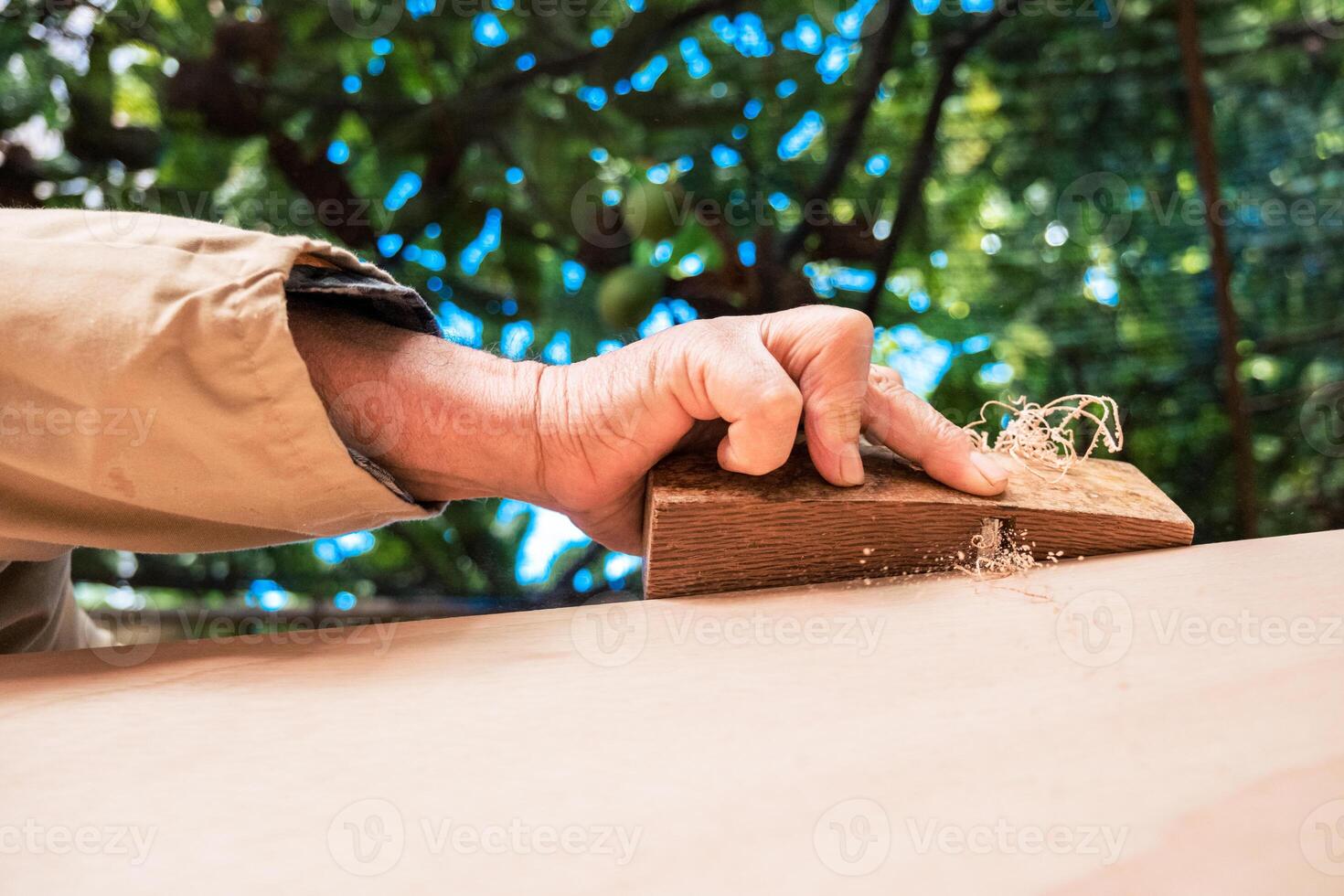 Anonymous senior man shaping wood with plane tool photo
