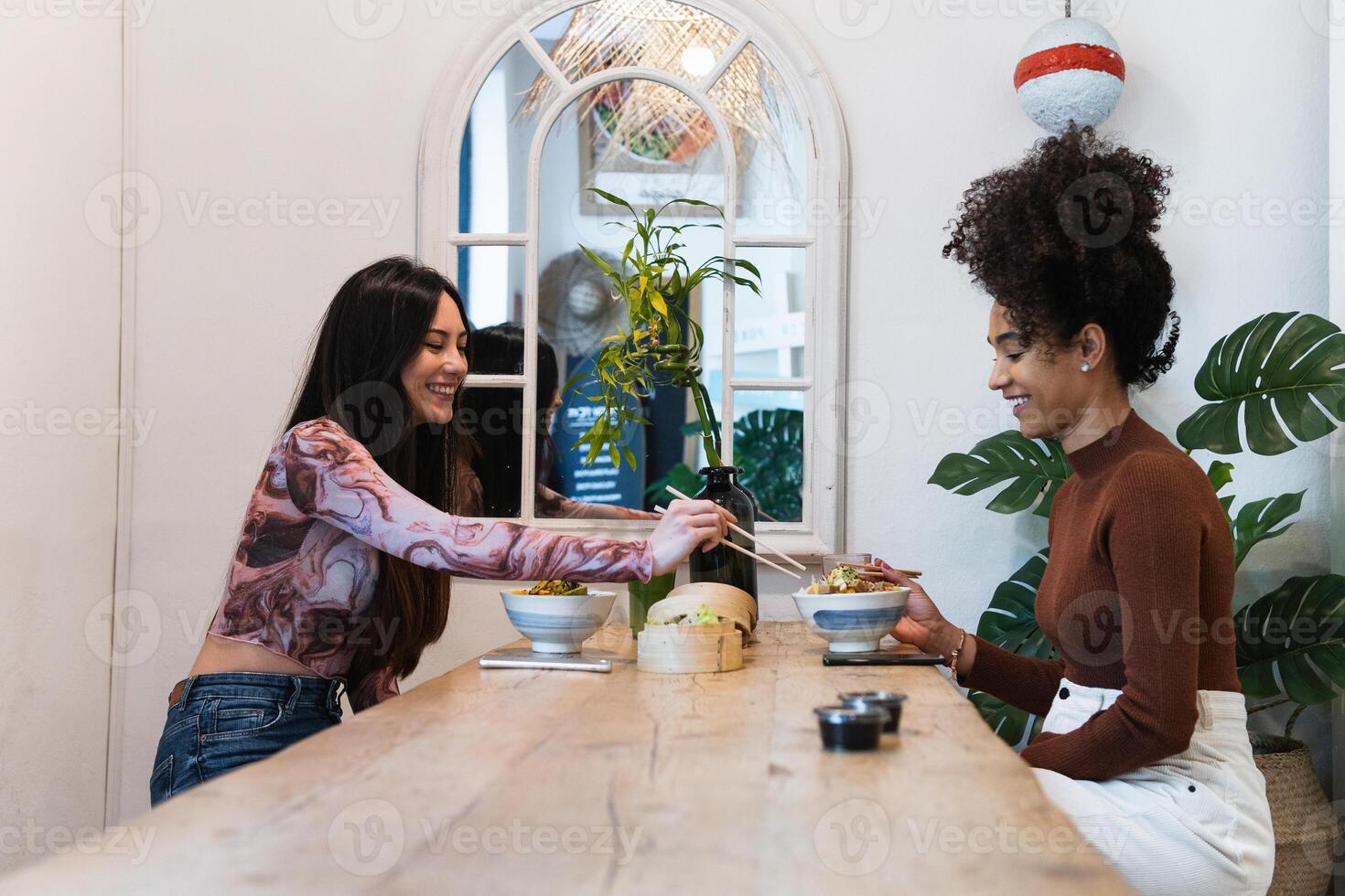 Delighted friendly multiethnic women eating in restaurant photo