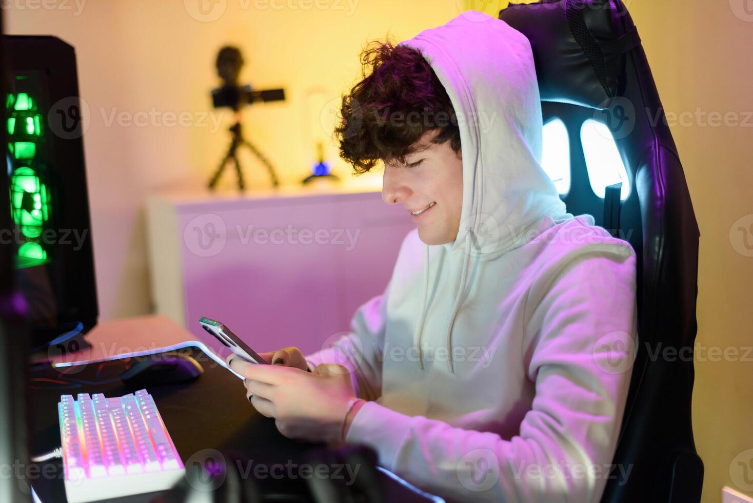 Focused happy young man sitting in chair and checking messages on smartphone photo