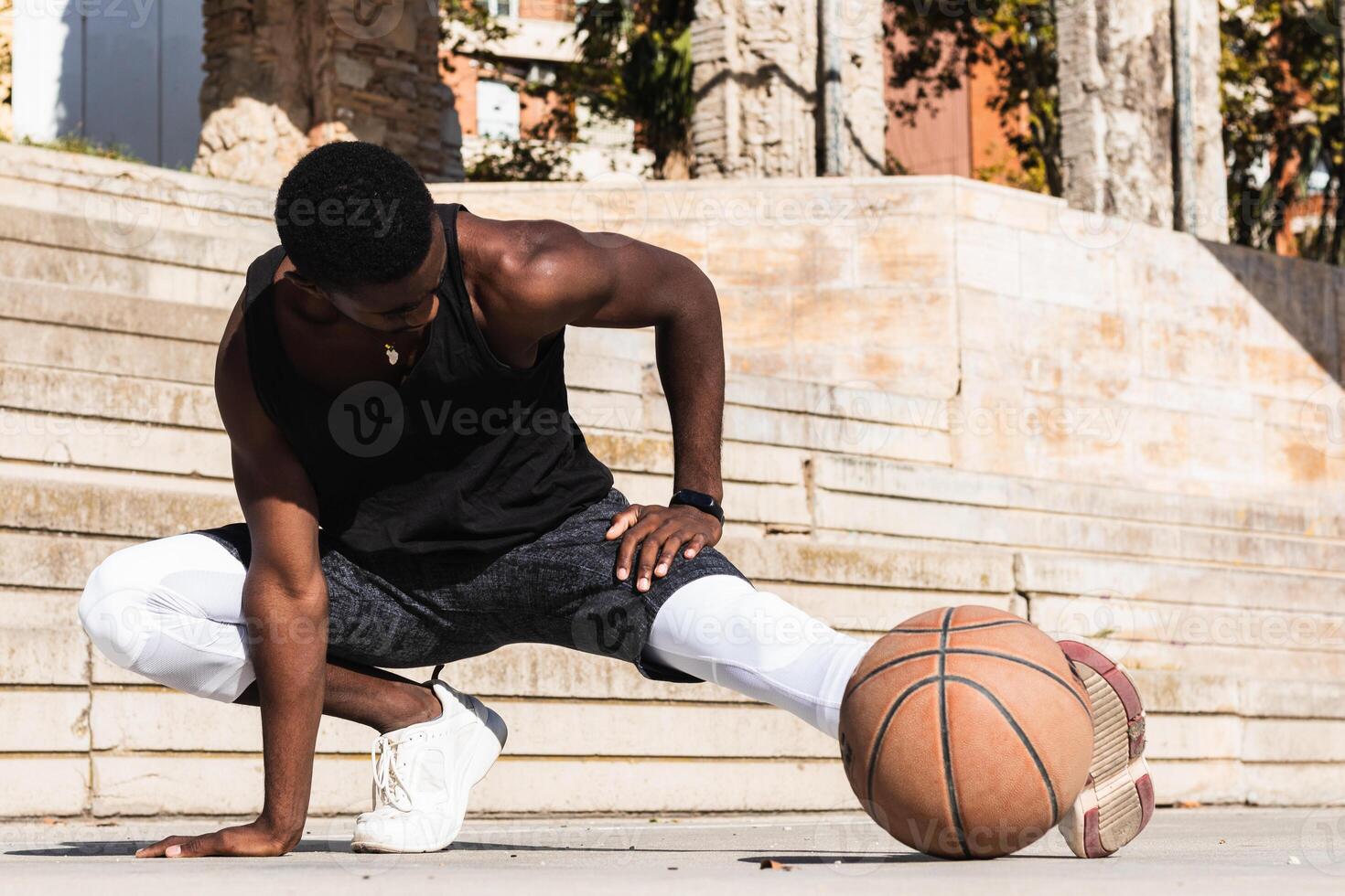 Black sportsman stretching on basketball court photo