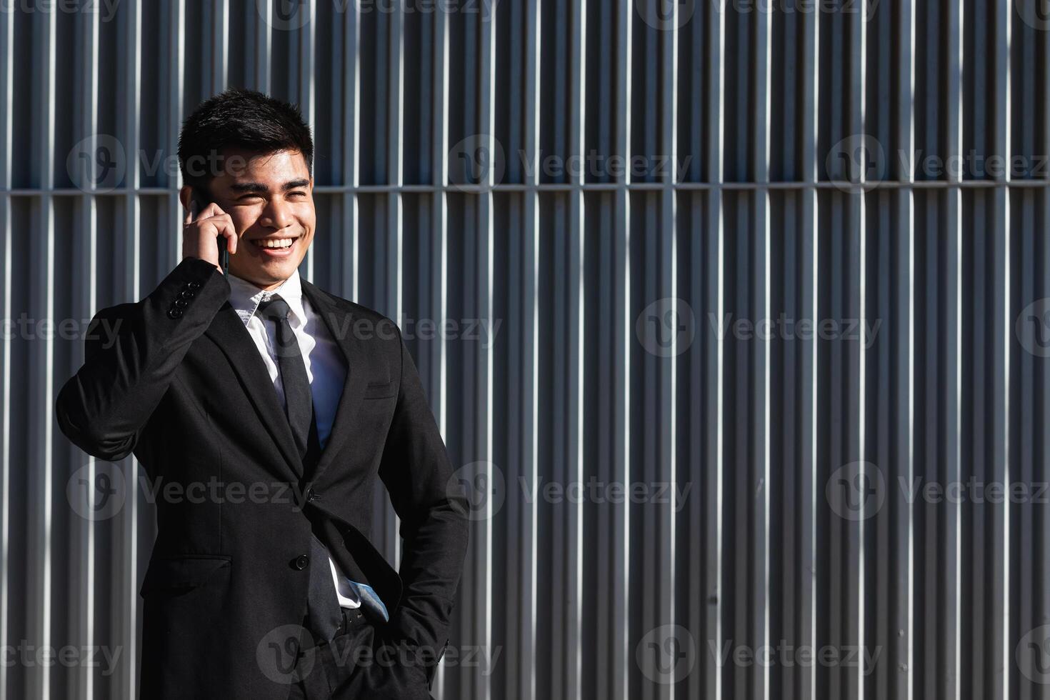 Smiling businessman speaking on smartphone in downtown photo