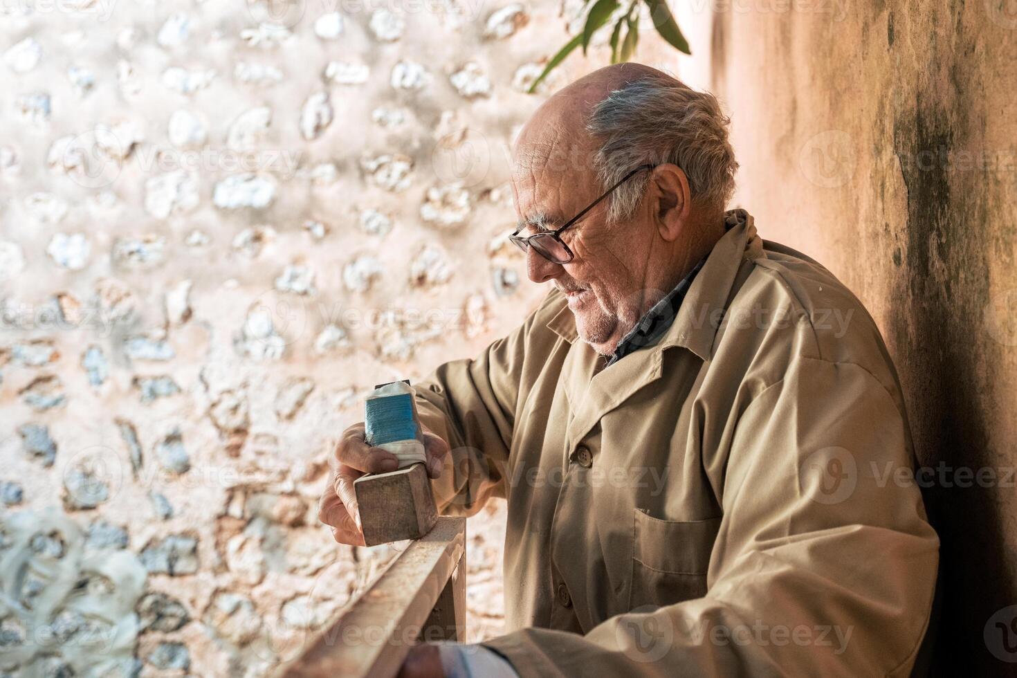 Senior man shaping wood with plane tool photo