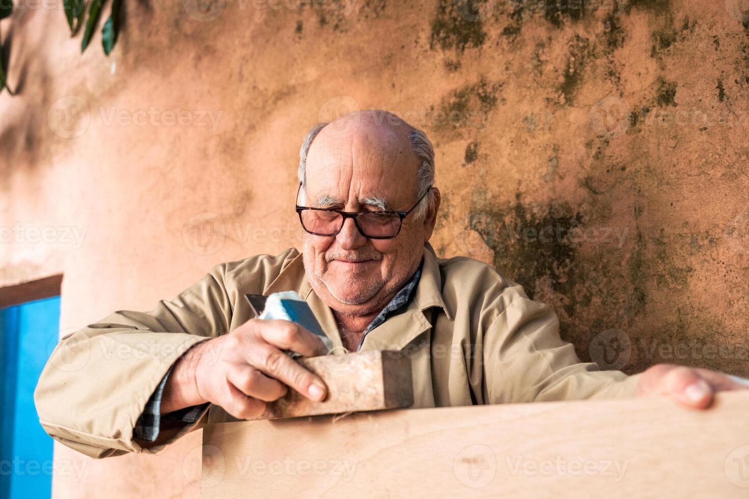 Senior man shaping wood with plane tool photo