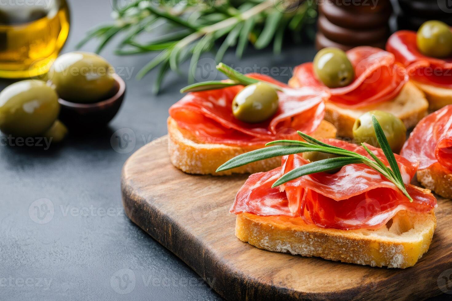 Spanish tapas with sliced sausage, olives and rosemary on toasted bread photo