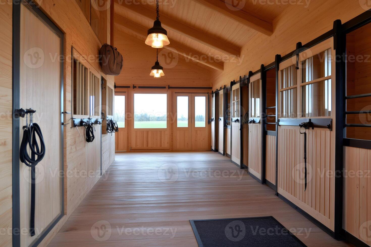 Horse stable interior showing empty stalls and tack room with hanging bridles photo