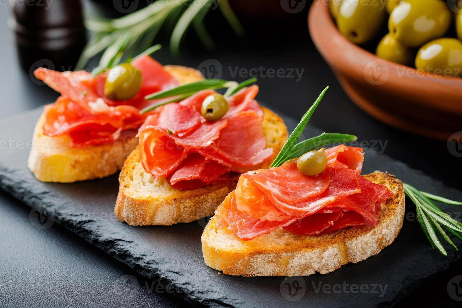 Tasty bruschetta with iberian ham, olives and rosemary ready to be served as tapas photo