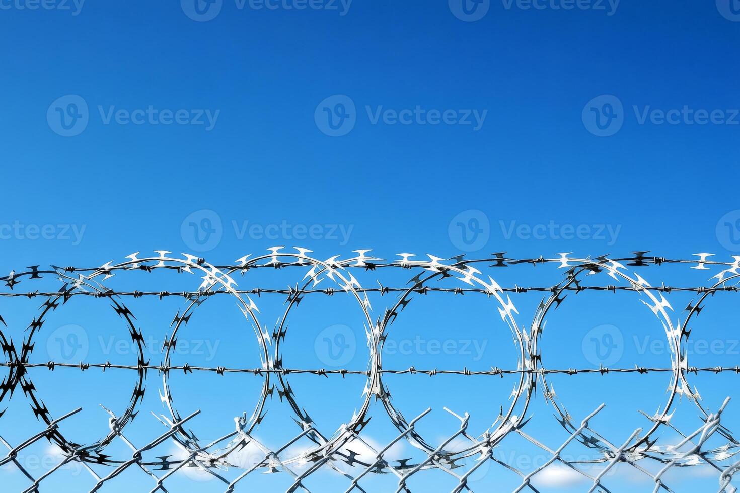 Razor wire forming protecting circles against a clear blue sky photo