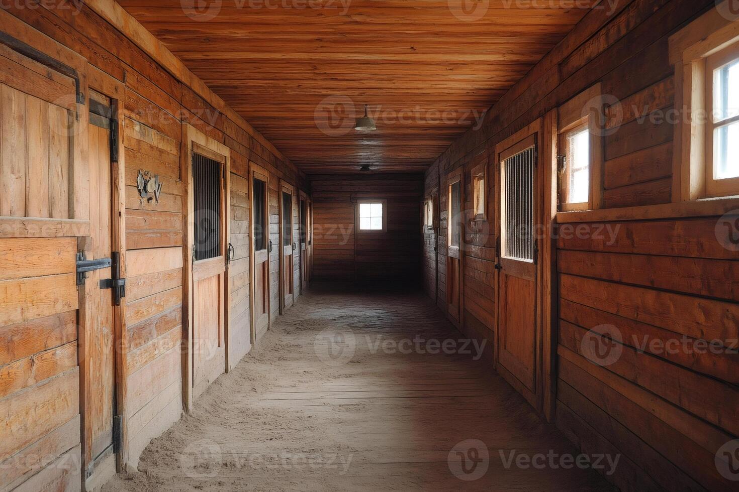 Empty horse stable interior showing stalls and sandy floor photo
