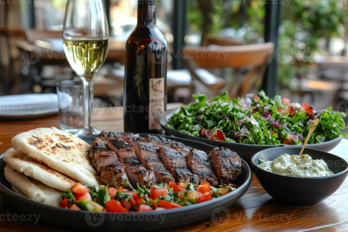Grilled lamb chops served with pita bread, salad, and white wine at restaurant table photo