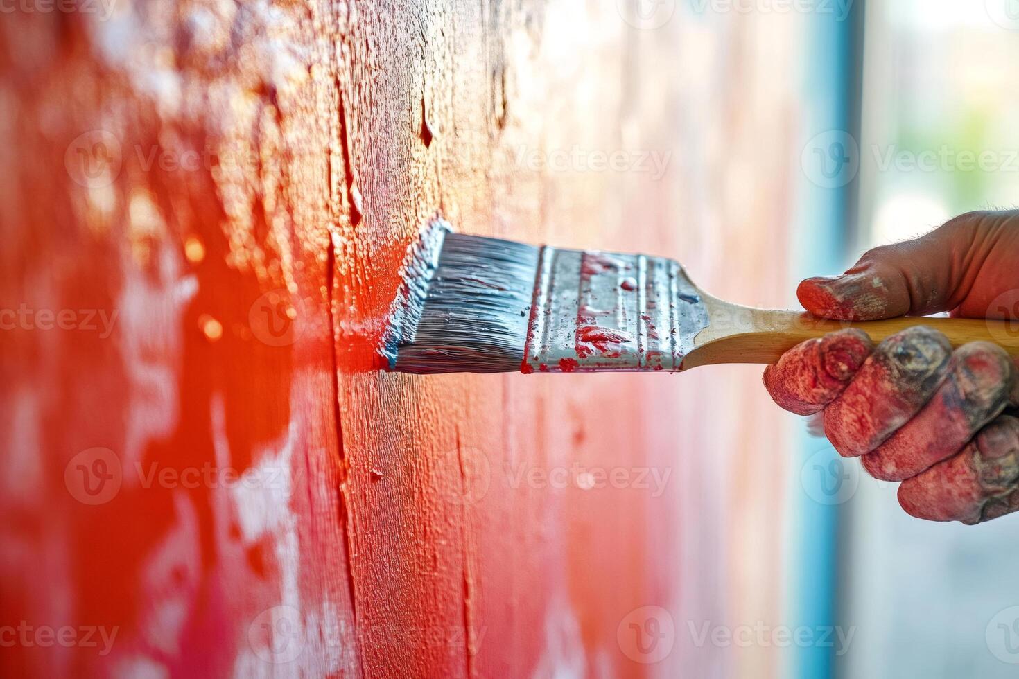 Painter applying red paint with brush on wall photo