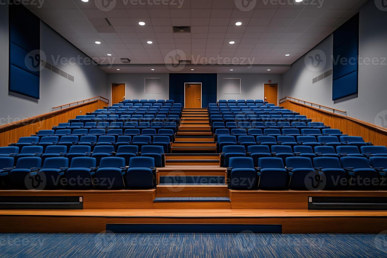 Empty auditorium with blue chairs and wooden steps awaits audience photo