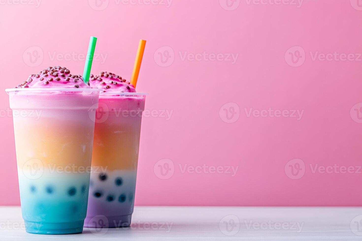 Two refreshing rainbow smoothies topped with pink whipped cream and chocolate sprinkles photo