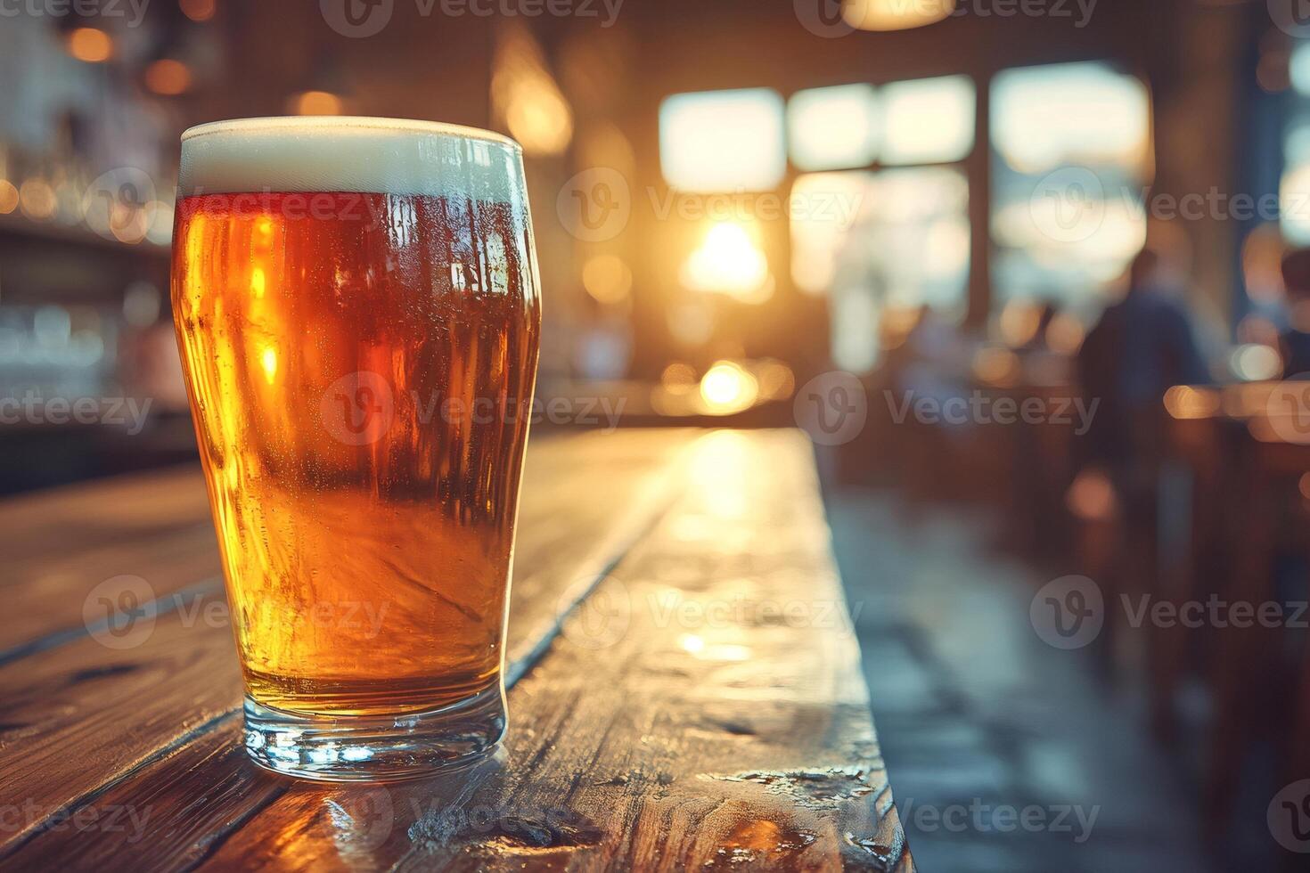 Glass of cold beer sitting on a wooden table in a pub at sunset photo