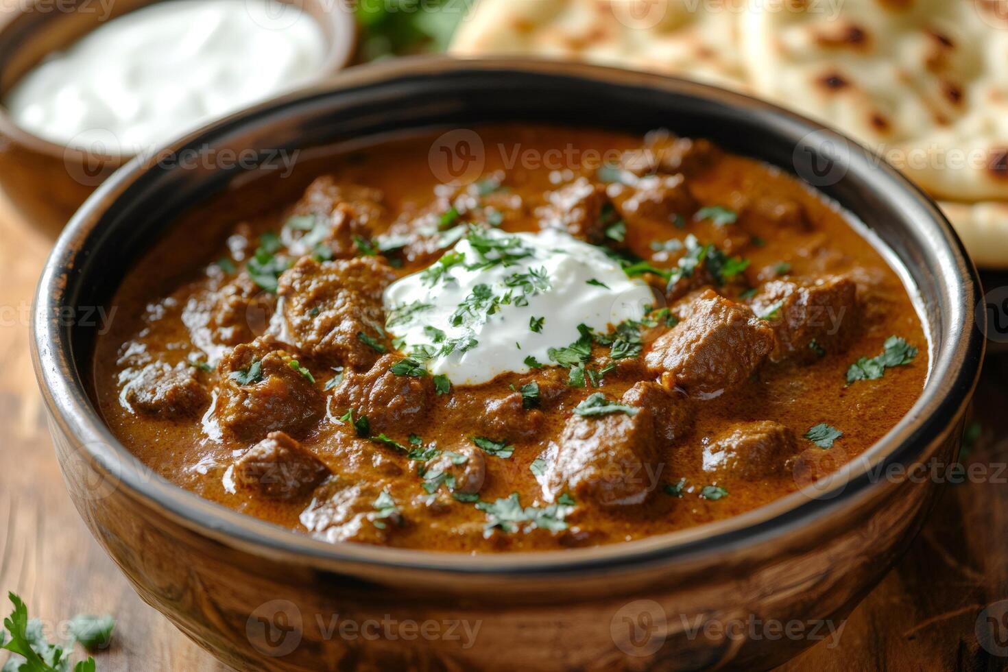 Delicious indian beef curry with yogurt and cilantro garnish, served with naan bread photo