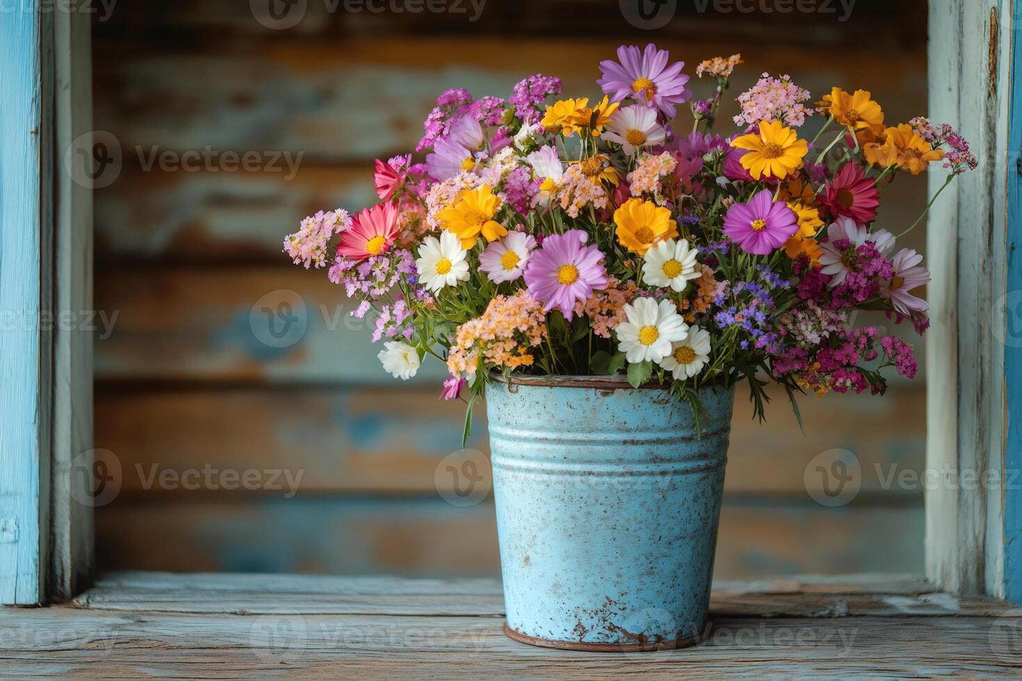 Colorful wildflowers filling a rustic blue bucket on wooden surface photo