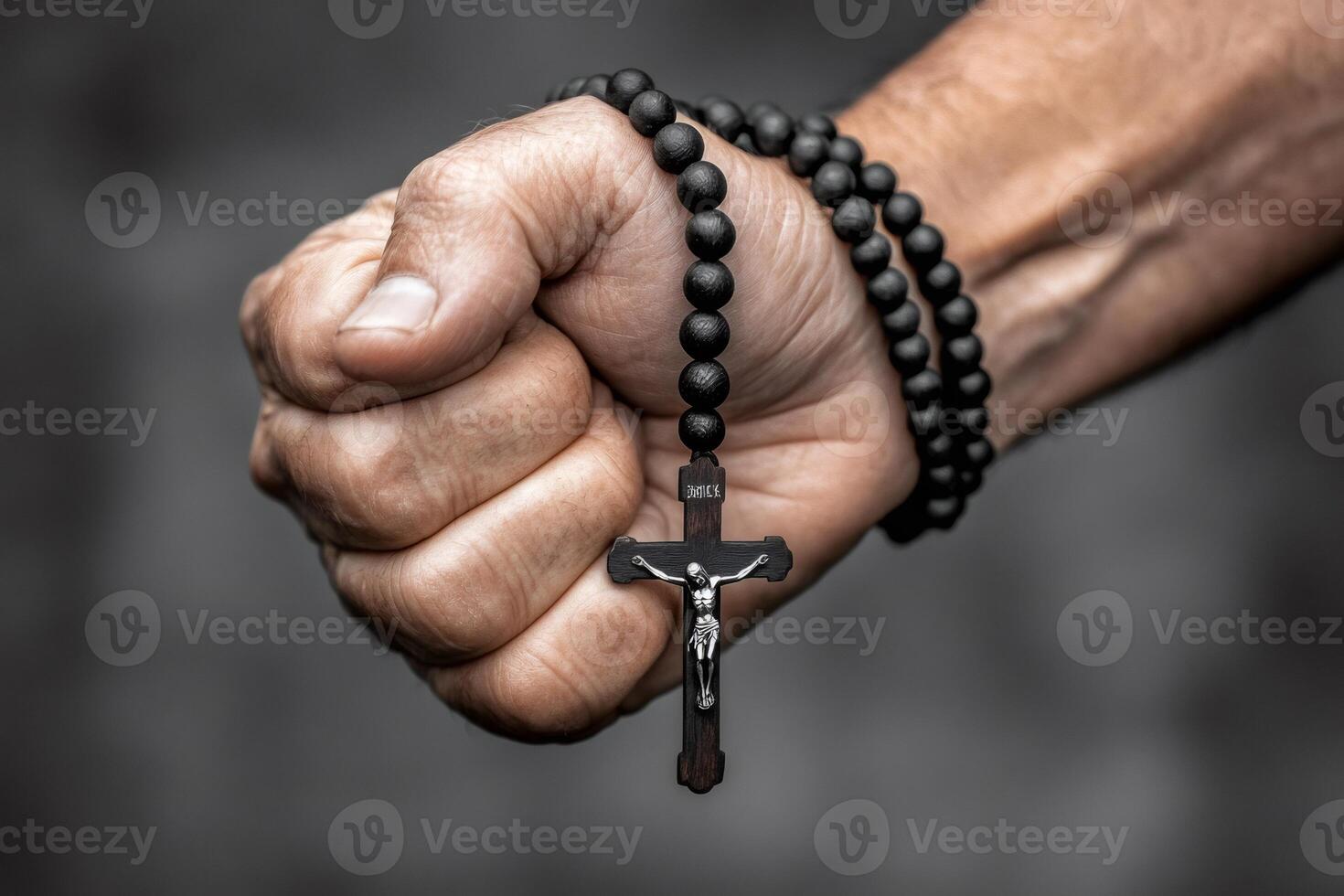 Hand holding wooden rosary and crucifix tightly, religious symbolism photo