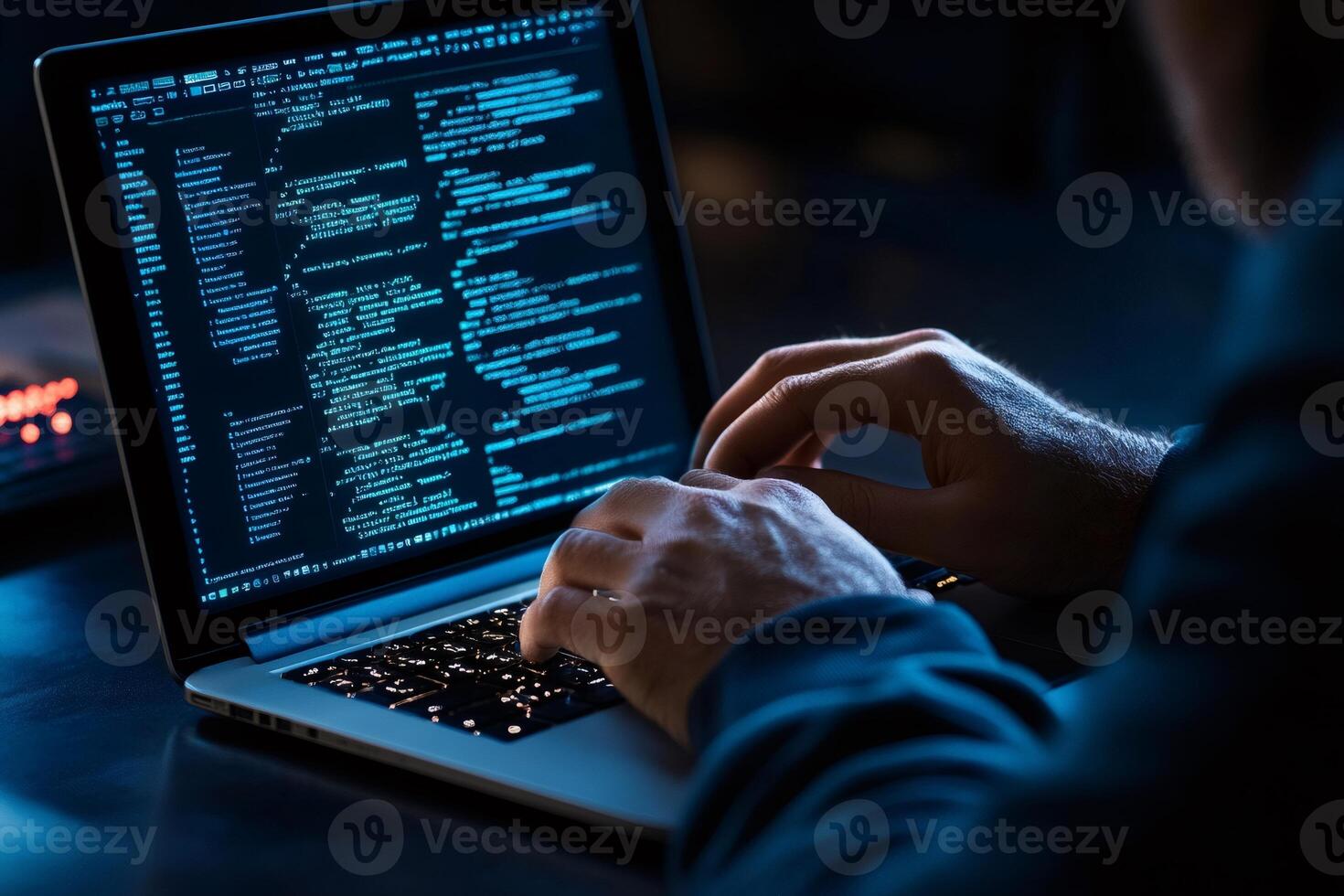 Programmer writing code on a laptop in a dark room photo